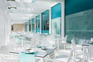 波连萨港MarSenses Puerto Pollensa Hotel & Spa的一间设有白色桌子和白色椅子的餐厅