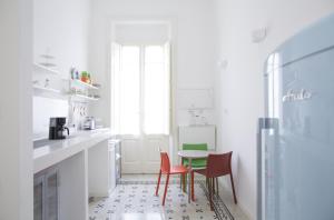 卡利亚里B&B Angioy 18的白色的厨房配有红色的椅子和桌子
