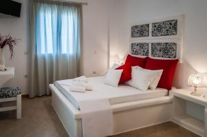 阿达玛斯Oceanis Rooms的卧室配有带红色枕头的大型白色床