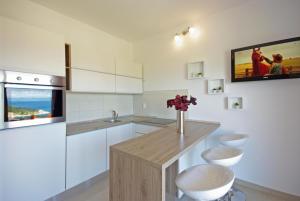 马卡尔斯卡Apartments Herceg的厨房配有白色橱柜和鲜花柜台。