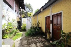 姆杜克Taman Ayu Homestay Munduk Mitra RedDoorz的黄色的房子,有木门和走道
