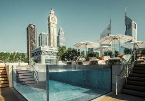 迪拜迪拜国际金融中心四季酒店的一座大楼的顶部,设有一座带椅子和遮阳伞的游泳池