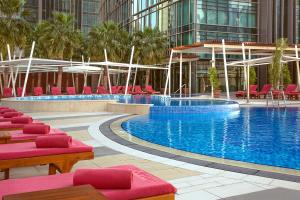 多哈多哈罗塔纳城市中心酒店的一座带红色椅子的游泳池和一座建筑