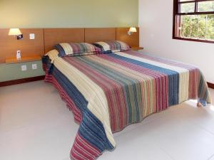 阿布拉奥Ancoradouro Flats的一间卧室配有一张大床和色彩缤纷的毯子