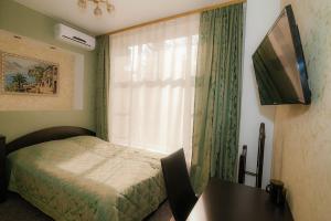 新库兹涅茨克Mini Hotel Voyage的一间卧室配有一张床、一台电视和一张桌子