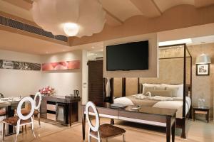 加尔各答Barsana Boutique Hotel - Pure vegetarian的一间卧室配有一张床、一张书桌和一台电视。