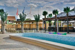 莱斯科瓦茨Hotel Bella Nella的棕榈树度假村的游泳池以及大楼