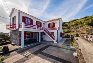 Calheta de NesquimAdega Pedra do Lagar的白色的房子,有红色的窗户和楼梯