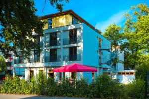 柏林柏林格律瑙大使酒店的蓝色的建筑,前面有粉红色的伞