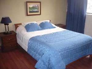 基多途塔曼达2旅馆的一间卧室配有一张带蓝色毯子的大床