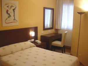 布尔戈斯阿康托酒店的一间卧室配有一张床、一张桌子和一把椅子