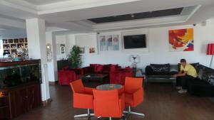 珊瑚湾Neptune Hotel Apartments Paphos的客厅配有红色椅子,沙发上坐着一个男人