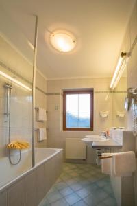 蒂罗尔州基希多夫纽沃特酒店的带浴缸、两个盥洗盆和淋浴的浴室。