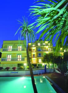 皮特拉利古莫瑞乐公寓式酒店的一座棕榈树在游泳池前的建筑