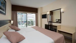 多列毛利诺斯Sandos Griego的配有一张床、一张书桌和一扇窗户的酒店客房