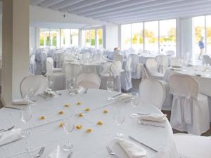 波米利亚诺达尔科Pietrabianca Exclusive Resort的一间装满白色桌椅、眼镜和餐巾的房间