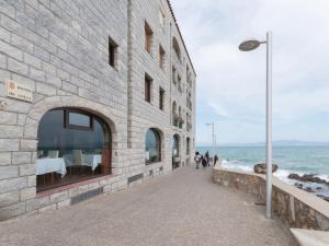 莱斯卡拉Belvilla by OYO Albatros 6的海边的砖砌建筑,人们沿着人行道走