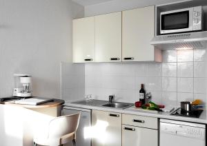 图卢兹At家庭公寓酒店的厨房配有白色橱柜、水槽和微波炉