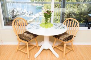 Madeira ParkMadeira Park Oceanview Suites的一张带两把椅子的白色桌子和花瓶