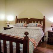 布罗肯希尔Heather's Mica Cottage的一间卧室配有一张带两个枕头的木床