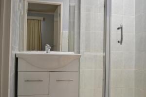 奥克利查斯顿行政汽车旅馆的白色的浴室设有水槽和淋浴。