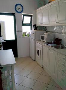 卡武埃鲁Erike Guest House的厨房配有白色橱柜、水槽和微波炉