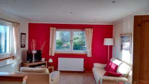 比尤利Ornum Cottage的客厅设有红色的墙壁和窗户