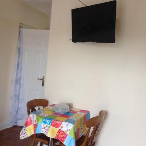 Lateeve拉提弗公寓的一张桌子,上面有五颜六色的桌布和墙上的电视机