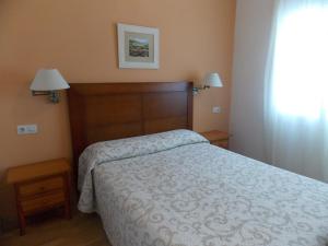 圣玛丽亚港Pensión La Palma的一间卧室配有一张床、两盏灯和一个窗户。