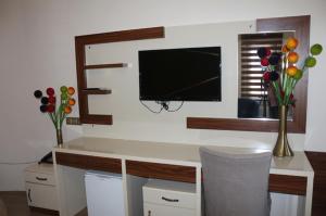 科尼亚麦斯奈维酒店的客房设有一张带电视和鲜花的书桌。