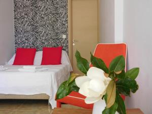 Apidias LakosAeolis Apartments & Studios的一间房间,配有床和两把红色椅子,还有植物