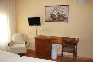 LarragaHotel Villa de Larraga的一间卧室配有一张桌子、一把椅子和一台电视机