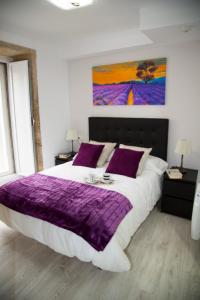圣地亚哥－德孔波斯特拉Xavestre Rooms Santiago的一间卧室配有一张大床、紫色毯子和枕头