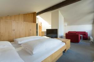 因斯布鲁克伊塞威特酒店的一间卧室设有两张床、一台电视和一张红色椅子。