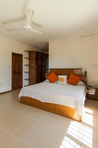 塔卡马卡夏洛特别墅　的卧室配有带橙色枕头的大型白色床