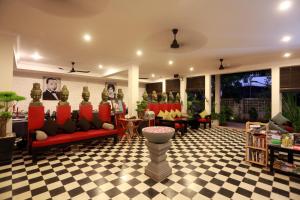 暹粒高棉公馆精品酒店的客厅设有红色沙发和 ⁇ 格地板