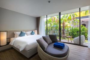华欣华欣艾希拉精品酒店的一间卧室配有一张床、一张沙发和一个窗口