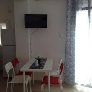 帕拉西亚斯Akrogiali Apartments的餐桌、椅子和墙上的电视