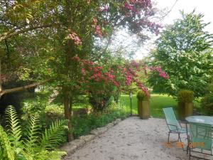 孔德诺森Les Chambres de la Nied的一个带桌椅的庭院,树下种有粉红色的花朵