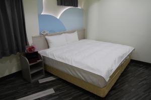 斗六市微旅时尚旅店的一张位于小房间的床,配有白色的床上用品