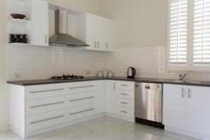 吉朗小迈尔斯的萨宾娜度假屋的厨房配有白色橱柜和不锈钢冰箱