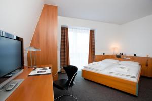 杜伊斯堡广场酒店 的一间卧室配有一张床和一张书桌及电视