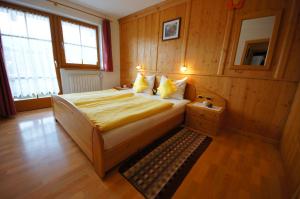 圣维吉利奥Gasthof La Pli Apartments的卧室配有一张床铺,位于带木墙的房间内
