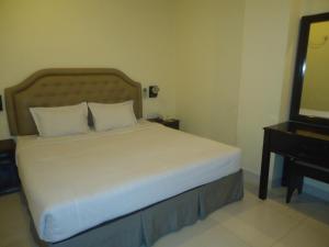 吉大港行政旅馆的一间卧室配有一张床、梳妆台和电视。
