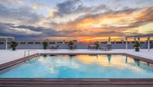 马尼拉Microtel by Wyndham UP Technohub的一座享有日落美景的建筑屋顶上的游泳池