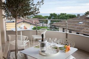 格拉多Suite & Spa Mirabel的阳台上的桌子上摆放着酒杯和一棵树