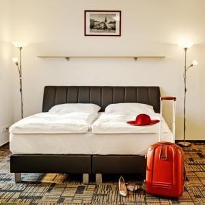 布尔诺eFi Palace Hotel的一间卧室配有一张带红色手提箱的床
