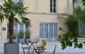 贝叶La Maison de Mathilde的一座带桌子和棕榈树的庭院,位于一座建筑前