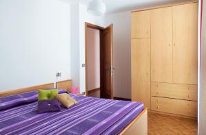 拉比Residence Bonetti的一间卧室配有一张紫色的床和一个木制橱柜