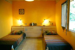 Salles-la-SourceGîte des Conquettes的橙色墙壁客房的两张床